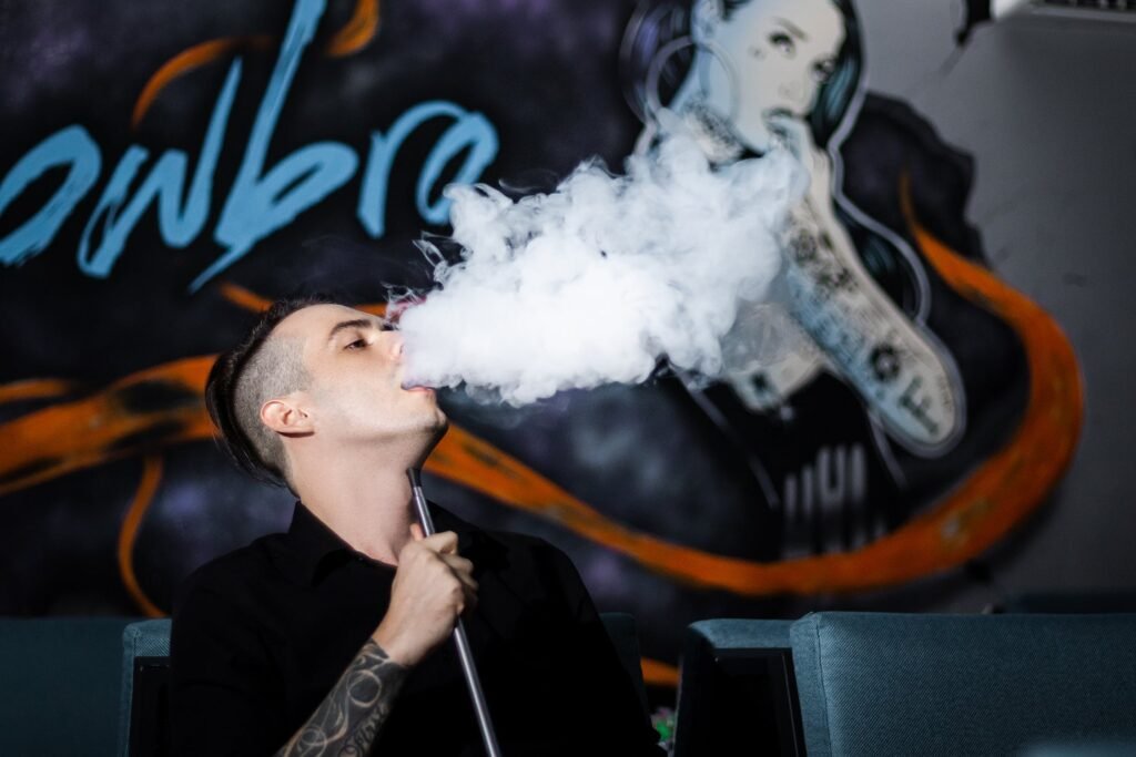 A man vaping with a vape device in his hand.